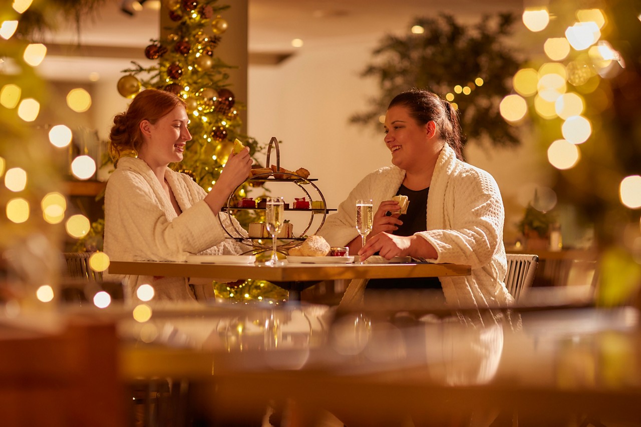 Two women eating a Festive Afternnon Tea in the Vitalé Café Bar.